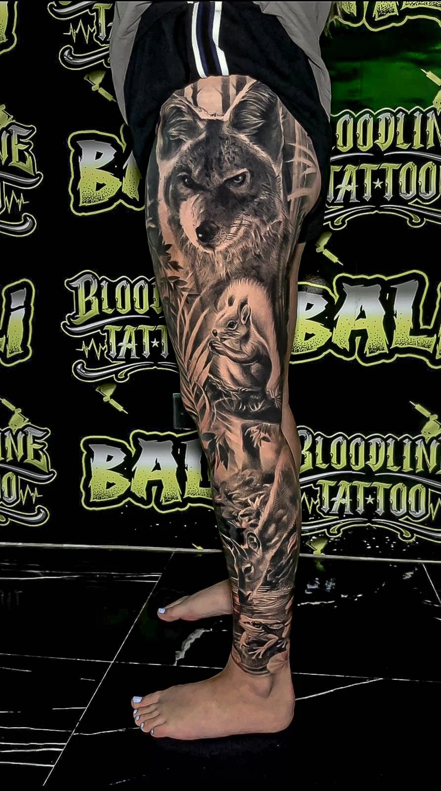 Healed wildlife leg sleeve with a wolf, squirrel, and forest scene, showing soft healed texture and clean subject separation at Bloodline Tattoo Bali.