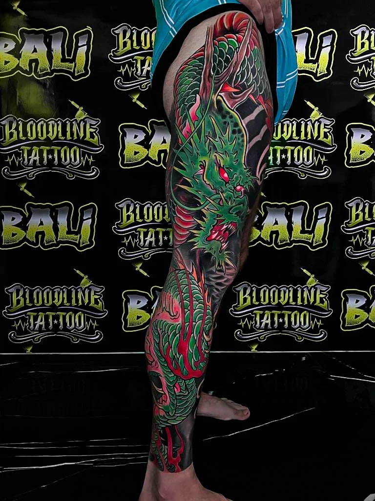 Healed color dragon leg sleeve with emerald scales and red flames, showing strong saturation and clean healed contours at Bloodline Tattoo Bali.