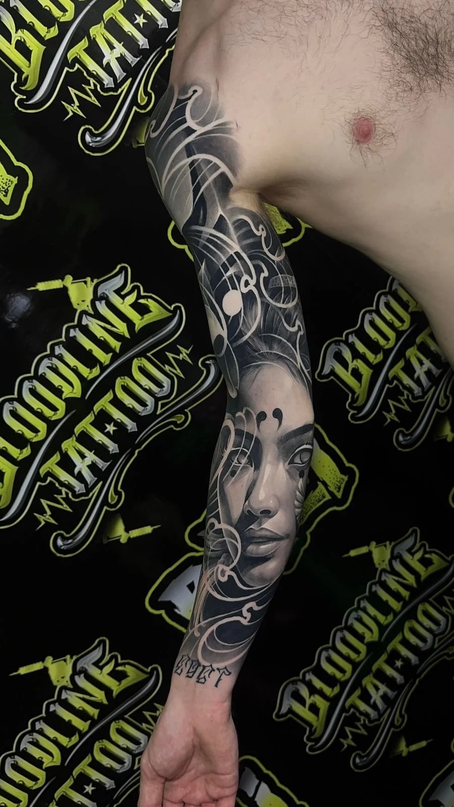 Healed abstract black-and-grey sleeve with swirling smoke forms and a female face, showing clean healed gradients and sharp edge control at Bloodline Tattoo Bali.