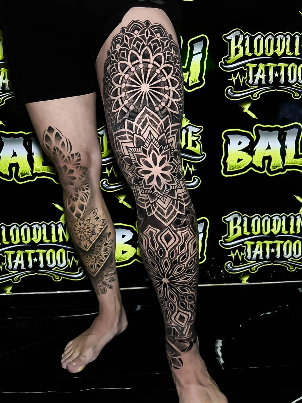 Full leg ornamental mandala sleeve with lotus rosettes, layered dotwork petals, and flowing negative-space geometry from thigh to shin at Bloodline Tattoo Bali.