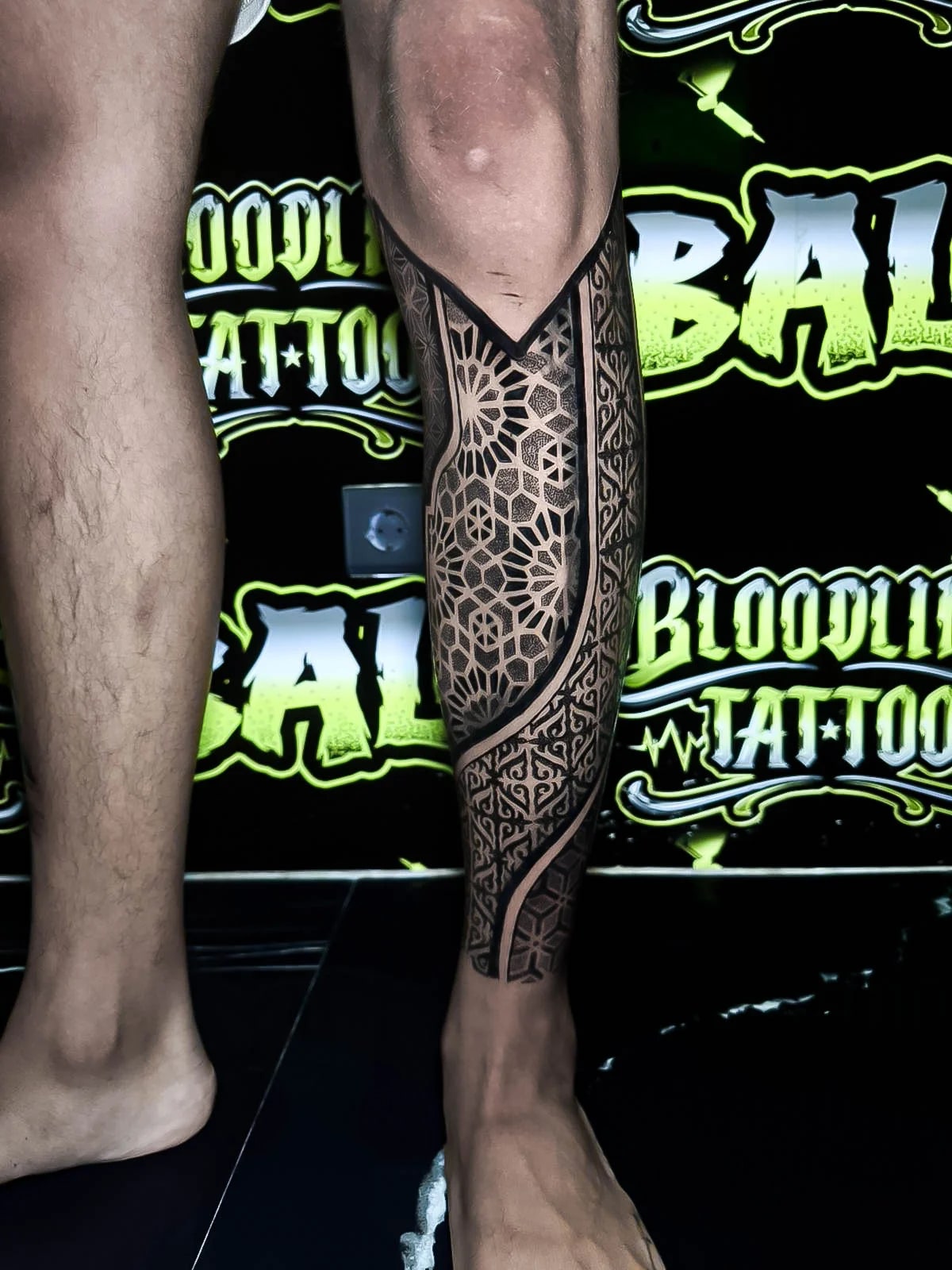 Geometric calf sleeve with hexagon webbing, ornamental borders, and crisp dotwork panels that hold sharp negative-space separation at Bloodline Tattoo Bali.