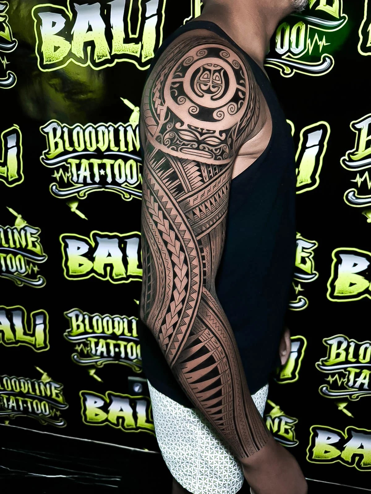 Polynesian-inspired arm sleeve with woven chevrons, spearhead bands, and bold blackwork flow wrapping cleanly from shoulder to forearm at Bloodline Tattoo Bali.