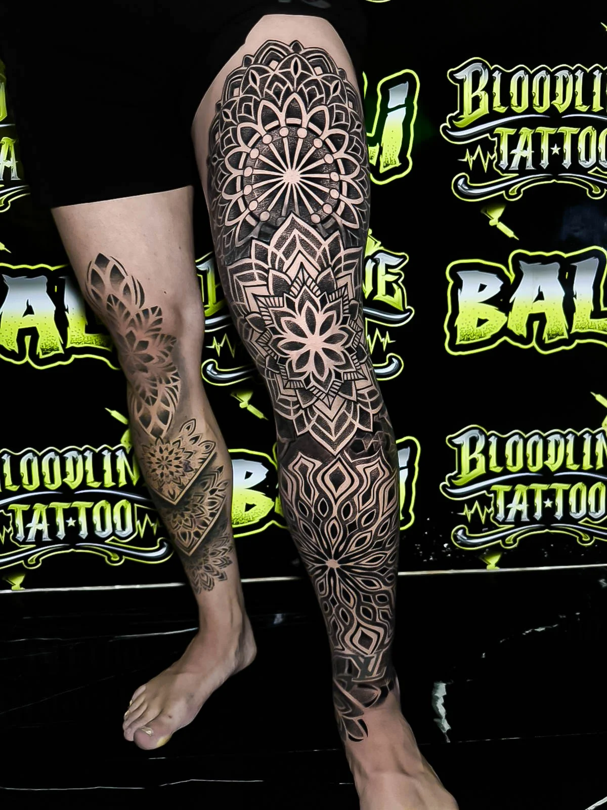 Full leg ornamental mandala sleeve with lotus rosettes, layered dotwork petals, and flowing negative-space geometry from thigh to shin at Bloodline Tattoo Bali.
